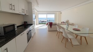 Una cucina moderna con mobili bianchi e un tavolo da pranzo in vetro.