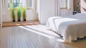 A bedroom with a large window, a bed, and a hanging light fixture. - Villa Les Eglantines in Belle Epoque Wijk Oostende (Oostende)