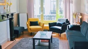 A modern living room with a wooden floor, a central coffee table, a sofa, and a yellow armchair. - Villa Les Eglantines in Belle Epoque Wijk Oostende (Oostende)