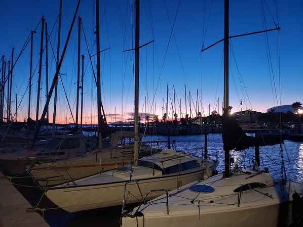 Un port de plaisance au crépuscule, où sont amarrés de nombreux voiliers.
