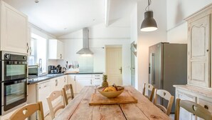 Una cocina moderna con armarios blancos, electrodomésticos de acero inoxidable y una mesa de comedor de madera.