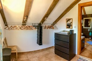 Une pièce avec un plafond orné de poutres en bois, un étendoir à linge, un meuble de rangement noir et un miroir au mur.