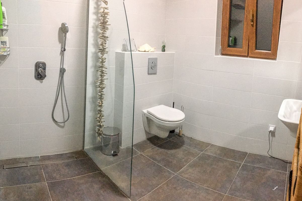 A bathroom with a glass shower enclosure, a toilet, and a sink.