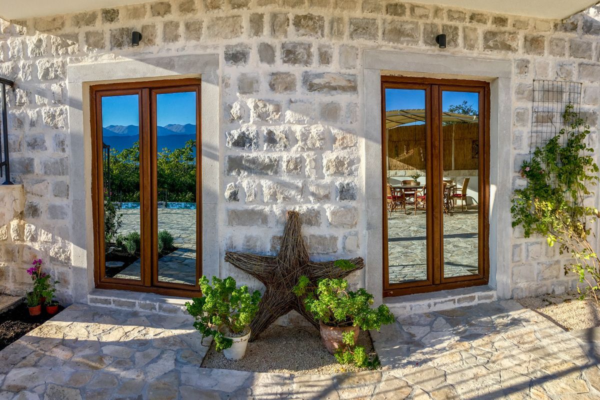 Un edificio de piedra con dos ventanas amplias, un adorno de estrella de mar y plantas en macetas.