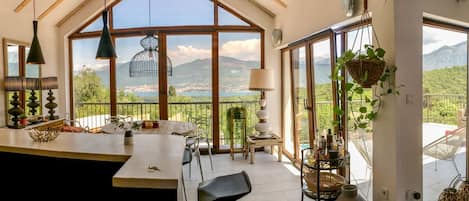 A spacious kitchen with a large island, a dining area with chairs, and a view of a mountainous landscape through large windows.