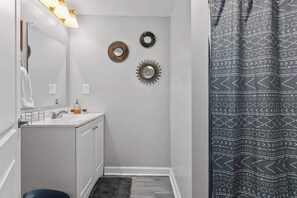 A bathroom with a white vanity, a mirror, and three wall-mounted decorative mirrors.