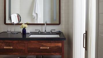 A bathroom with a wooden vanity, two sinks, a large mirror, and a towel rack.