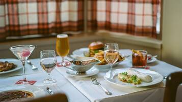 A dining table set with various dishes, glasses, and cutlery, with plaid curtains in the background.