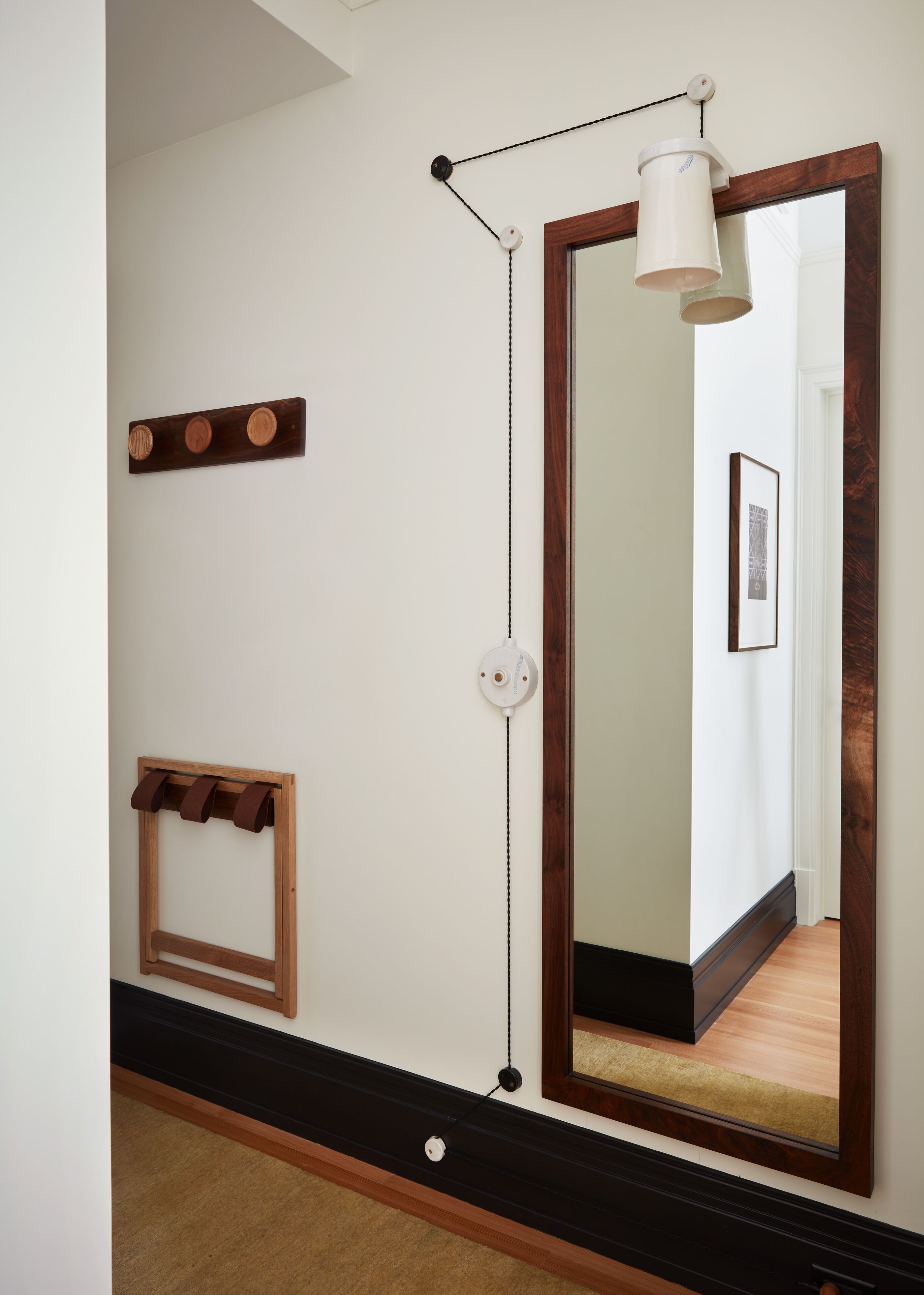 A hallway with a large mirror, a coat rack, and a wall-mounted light fixture.