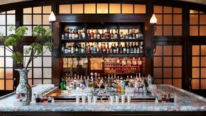 A bar with a marble countertop, multiple stools, and a clock above. - Nine Orchard (New York)