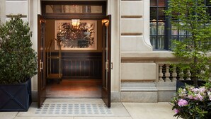 A grand entrance with a covered walkway, a large window, and a decorative wall piece. - Nine Orchard (New York)