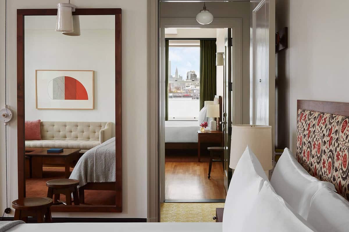 Ein Hotelzimmer mit Bett, einer Couch, einem Esstisch und Blick auf die Stadt.