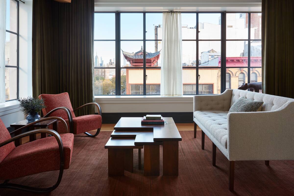 Ein modernes Wohnzimmer mit großem Fenster, Holzmöbeln und Blick auf traditionelle Architektur.