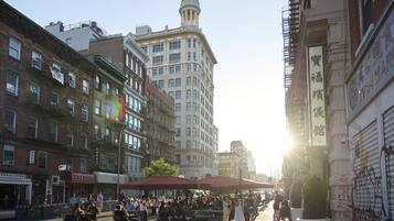A busy urban street with historic buildings, outdoor seating, and a prominent clock tower.