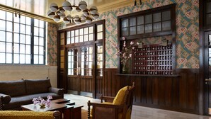 A traditional interior with a sofa, armchairs, a wooden coffee table, and a decorative vase. - Nine Orchard (New York)