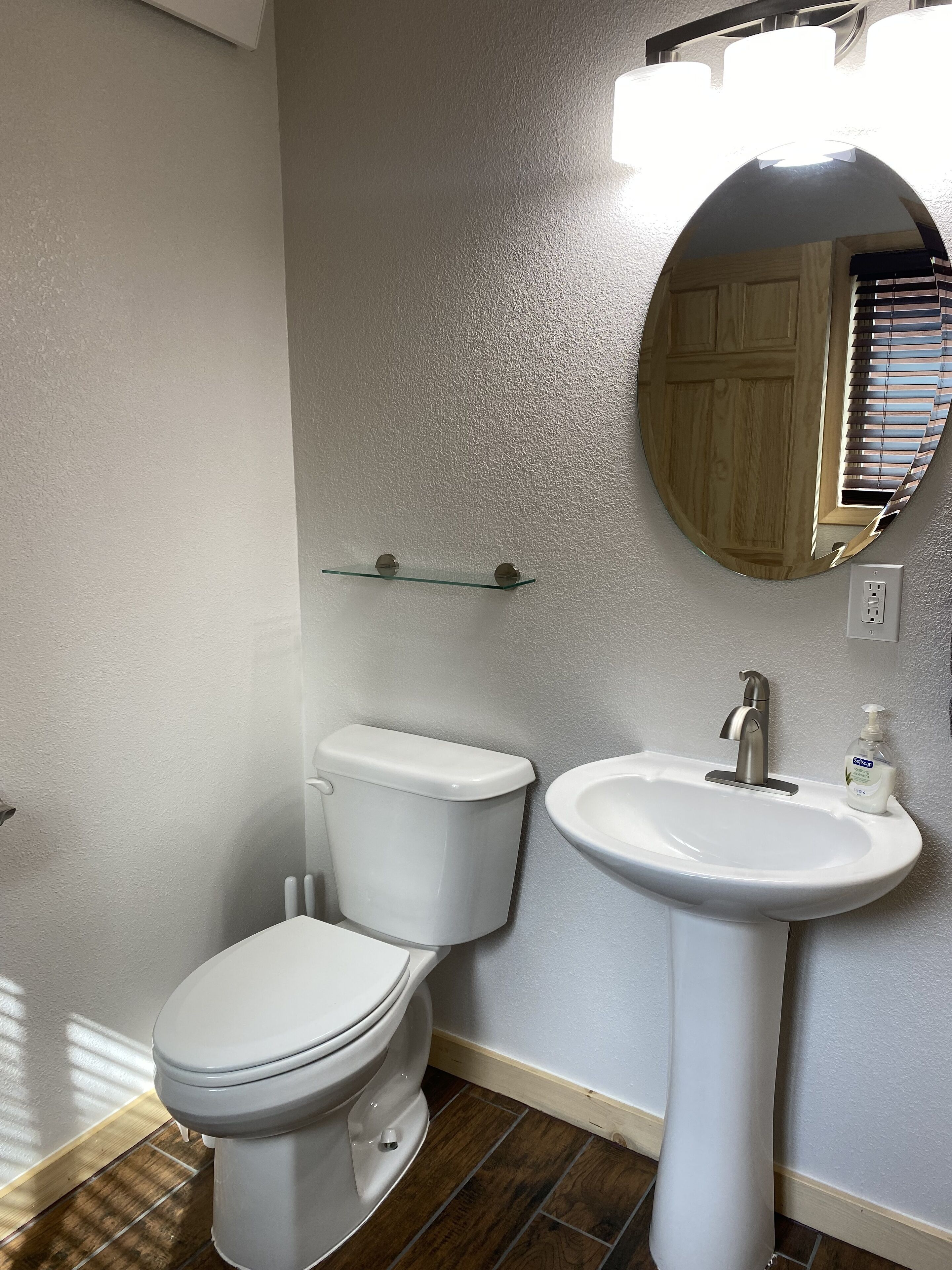 Et badeværelse med toilet, vask og spejl.