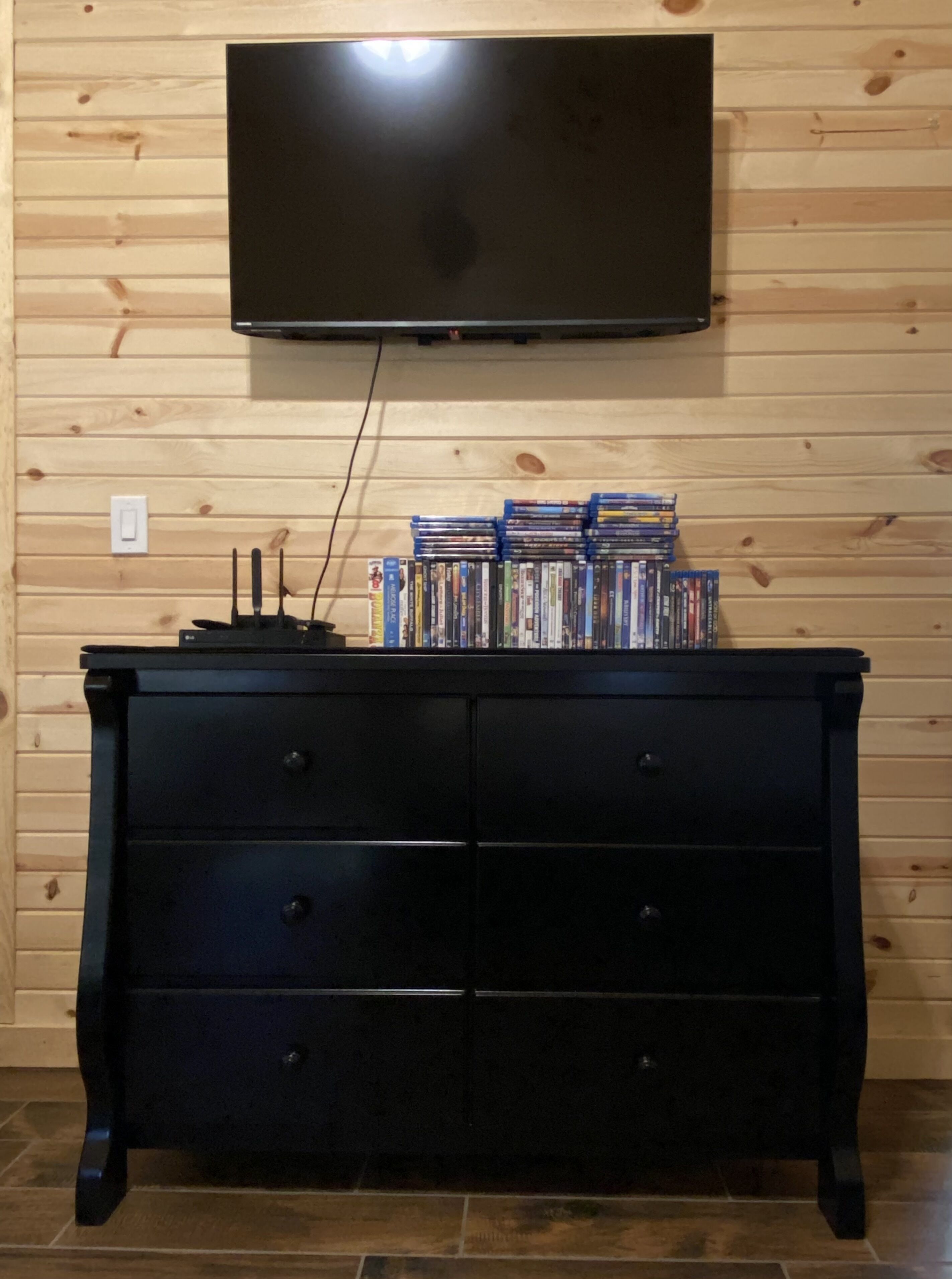 Pared de paneles de madera con un televisor de pantalla plana montado sobre un aparador negro.