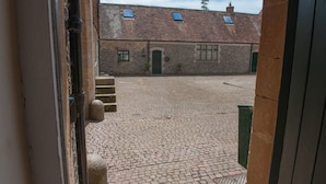 A courtyard with cobblestone paving, a brick building with a green door, and a small garden area. - Fine period home on country estate, Lyme Regis (Lyme Regis)