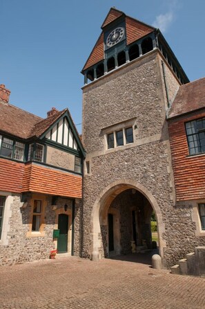 A historic stone building with a clock tower, a central archway, and traditional timber framing. - Fine period home on country estate, Lyme Regis (Lyme Regis)