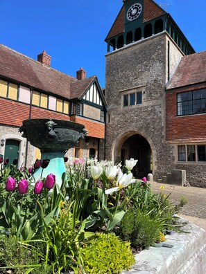 A historic building with a clock tower, a stone facade, and a fountain with flowers. - Fine period home on country estate, Lyme Regis (Lyme Regis)