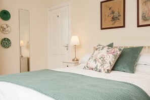 A neatly arranged bedroom with a bed, a bedside table with a lamp, and a door. - Fine period home on country estate, Lyme Regis (Lyme Regis)