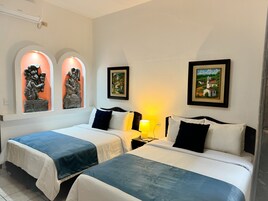 Una habitación de hotel con dos camas, una mesita de noche, una lámpara y obras de arte en las paredes.