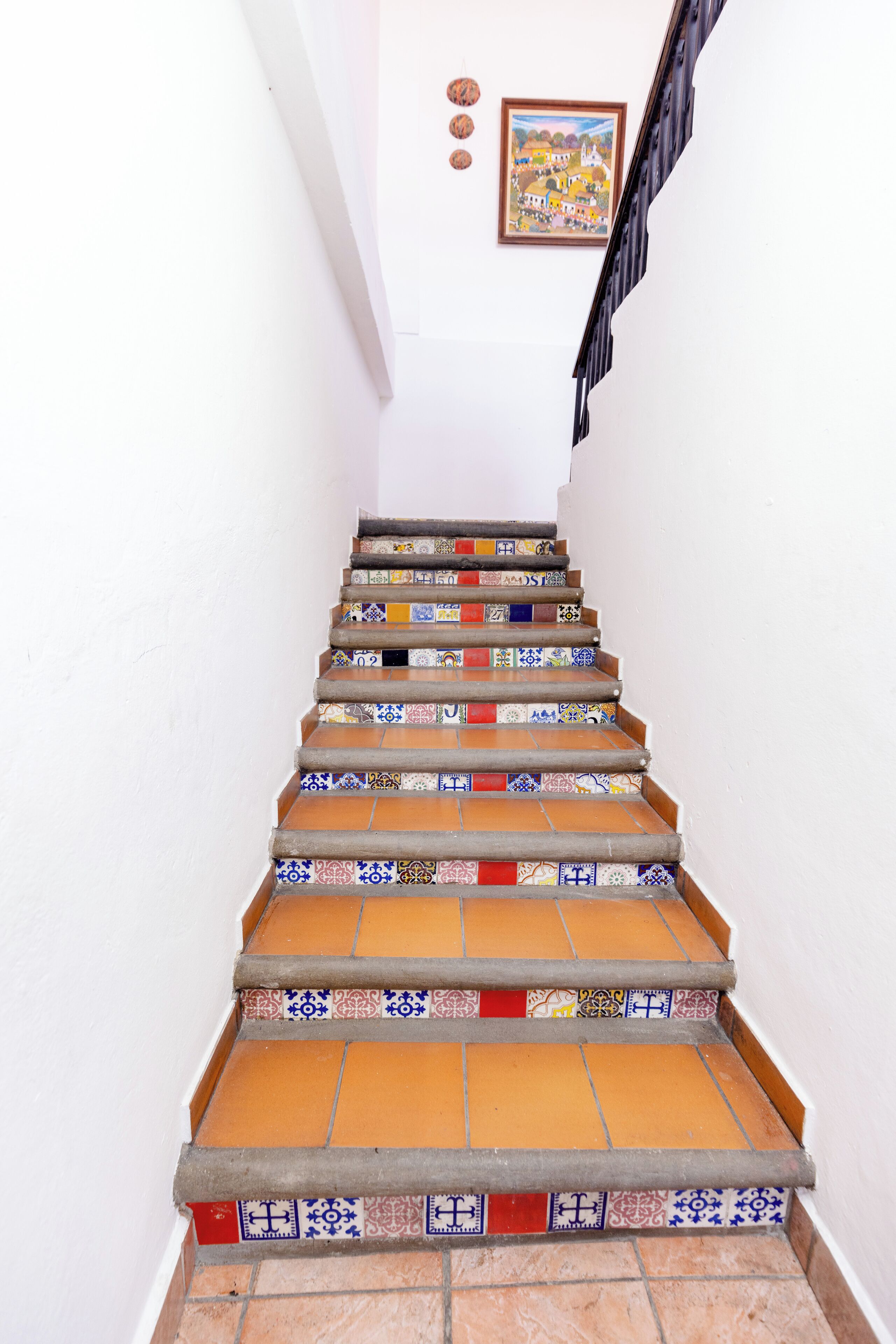 Una escalera con baldosas de colores y un cuadro enmarcado en la pared.