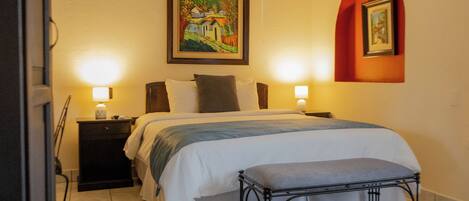A neatly arranged bedroom with a bed, bedside tables, a bench, and two wall-mounted lamps.