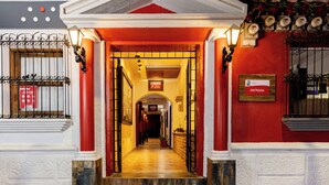 A hotel entrance with a red facade, a sign reading "ENTRADA," and a tiled floor leading into the building. - Hotel Camino Maya (Copan Ruinas)