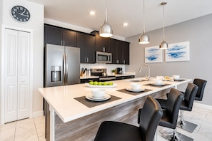 A modern kitchen with dark cabinets, stainless steel appliances, and a central island with seating.
