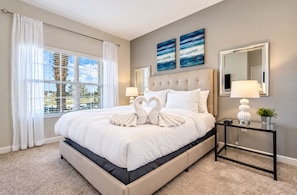 A hotel room with a large bed, a nightstand with a lamp, a mirror, and two wall art pieces.