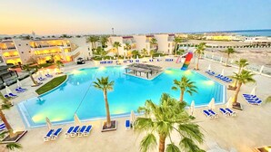 A large swimming pool with sun loungers and palm trees, surrounded by buildings with balconies. - Ivy Cyrene Island Aqua Park Resort (Sharm El Sheikh)