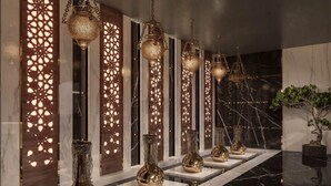 A hallway with a series of golden vases on display, a reflective marble floor, and decorative panels with intricate cut-out patterns. - Ivy Cyrene Island Aqua Park Resort (Sharm El Sheikh)