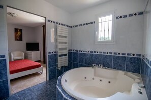 Relax in a spacious bathroom with a bathtub and a window with bars.