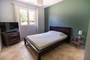 Cozy retreat with a dark wooden bed frame, television, and nightstand, set against a serene backdrop.