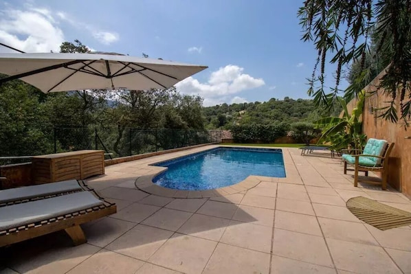 Relax by the pool surrounded by a patio with lounge chairs and a bench.