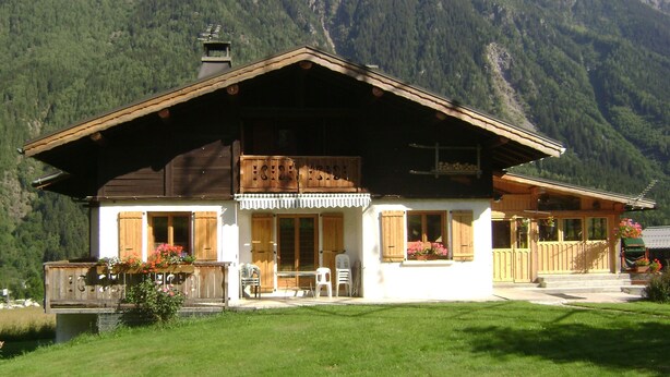 A two-story wooden chalet with a balcony, surrounded by lush greenery and mountains. - Studio Aux Bossons (3km From Chamonix Mont Blanc ) (Chamonix Mont-Blanc)