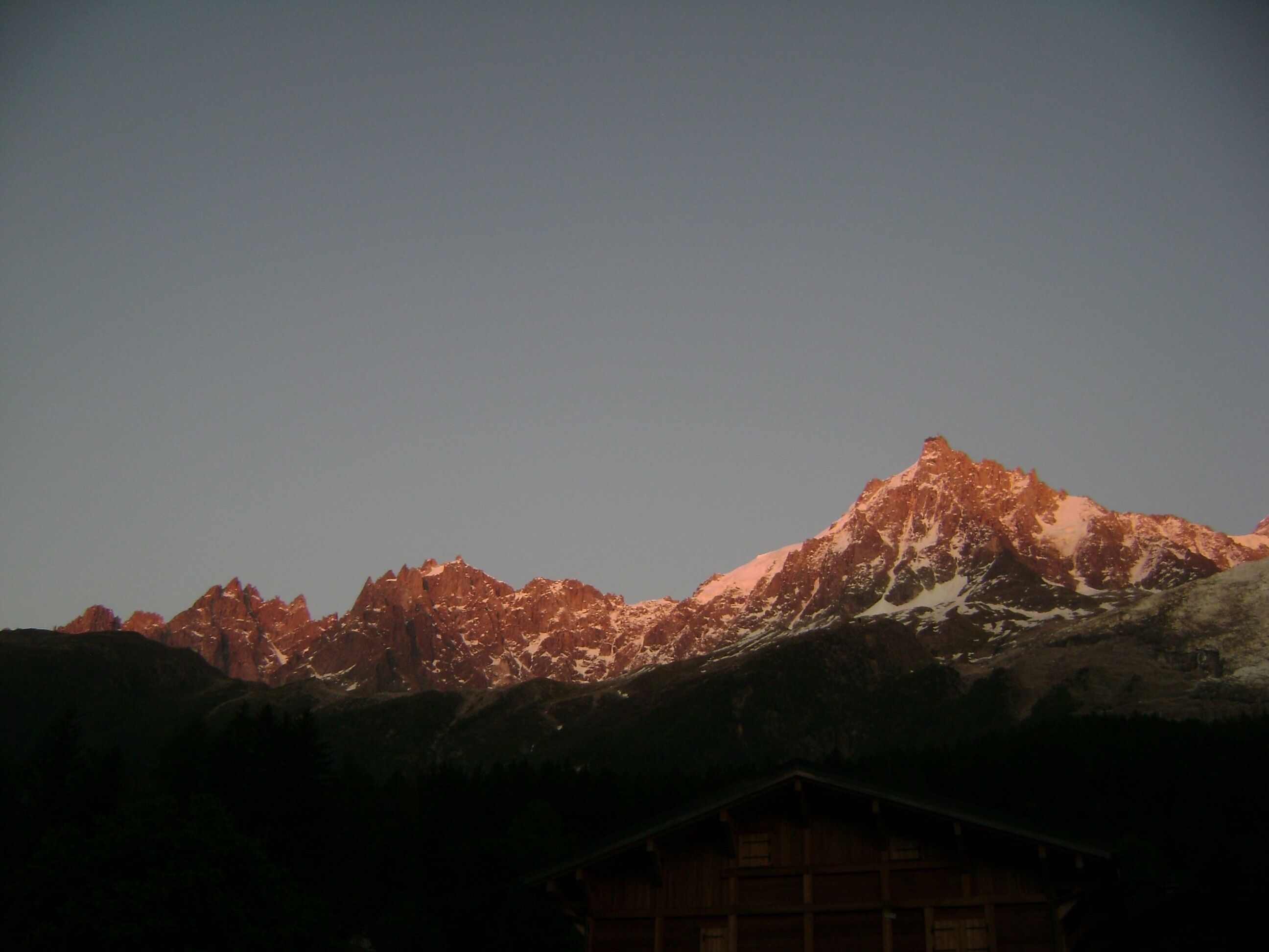 A mountain range with a cabin in the foreground.
