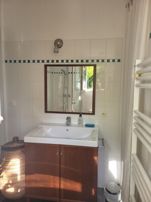 A bathroom with a white sink, a mirror, and a shower enclosure.