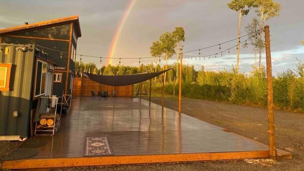 Eine rustikale Holzhütte mit einer Veranda, einer Hängematte und einer Lichterkette.
