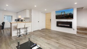 Een moderne keuken met witte kasten, een houten deur en een grote flatscreen televisie boven een open haard.