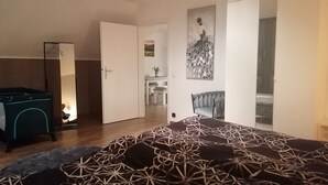 Una camera da letto con un letto, una sedia, una scrivania e una porta che dà su un'altra stanza.