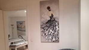 Una stanza con una poltrona imbottita blu, un quadro di una ballerina e un pavimento in legno.
