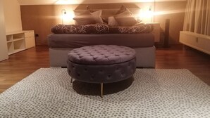 Una camera da letto con un letto, un comodino, una cassettiera, una finestra con tende e un termosifone.