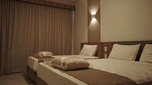 A hotel room with two beds, a nightstand, and a wall-mounted light. - Privé Praias do Lago Eco Resort (Caldas Novas)