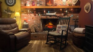 A cozy living room with a brick fireplace, leather armchair, and a rocking chair.