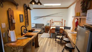 A cozy kitchen with wooden countertops, a dining area with a wooden table and chairs, and a refrigerator.