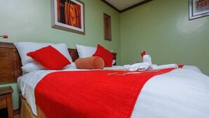 A neatly made bed with red and white bedding, a wooden headboard, and a red throw blanket.