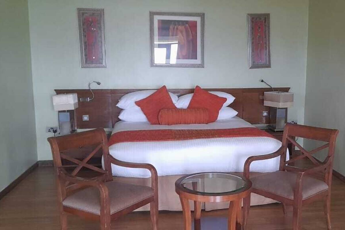 A bedroom with a bed, two chairs, a small table, and a nightstand.