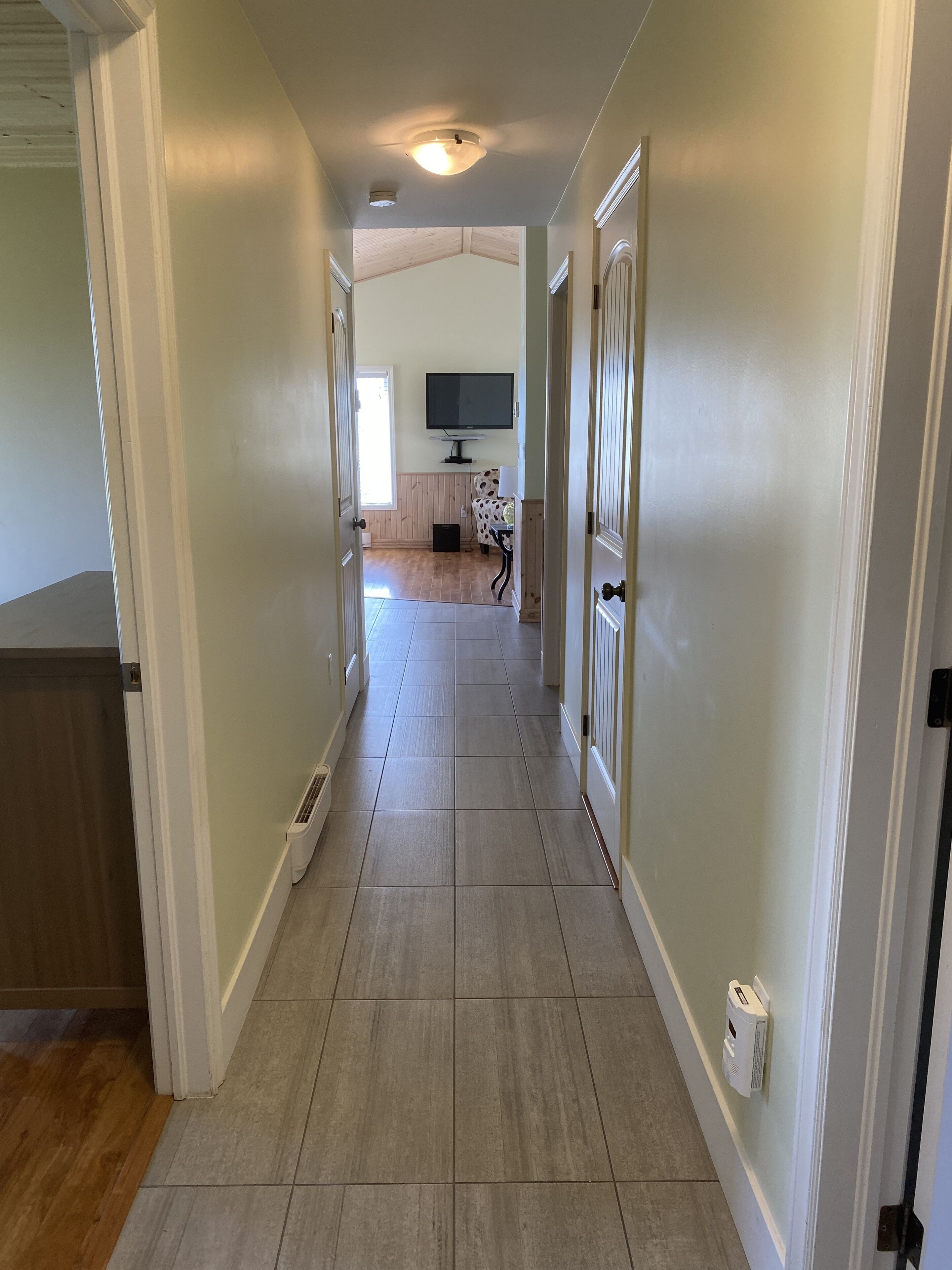 A hallway with a tiled floor, white walls, and a ceiling light.